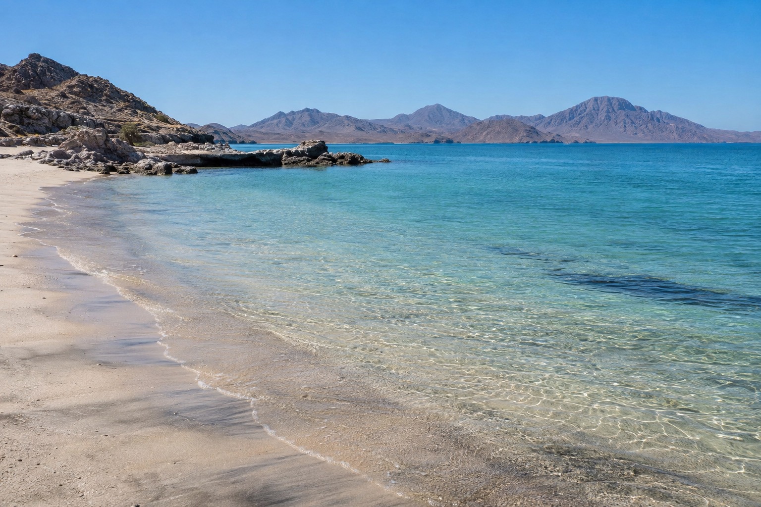 Empty sandy beach with calm turquoise water under a clear sky on the Sea of Cortez
