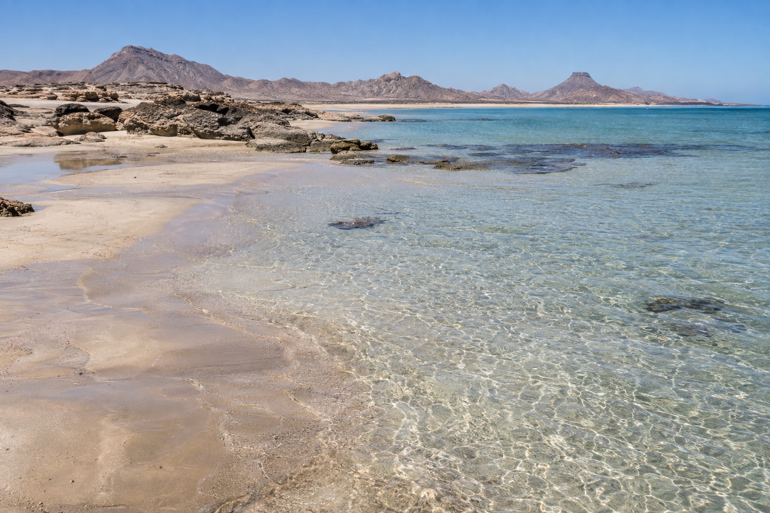 Shallow water and pale sand along a desert shoreline near Puerto Penasco at midday