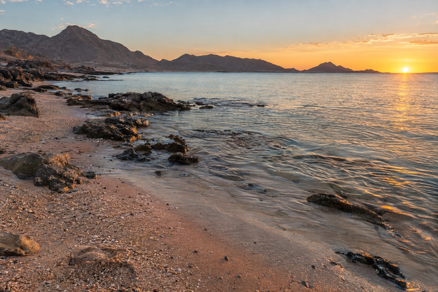 Sandy shoreline and calm shallow water on the Sea of Cortez at low sun