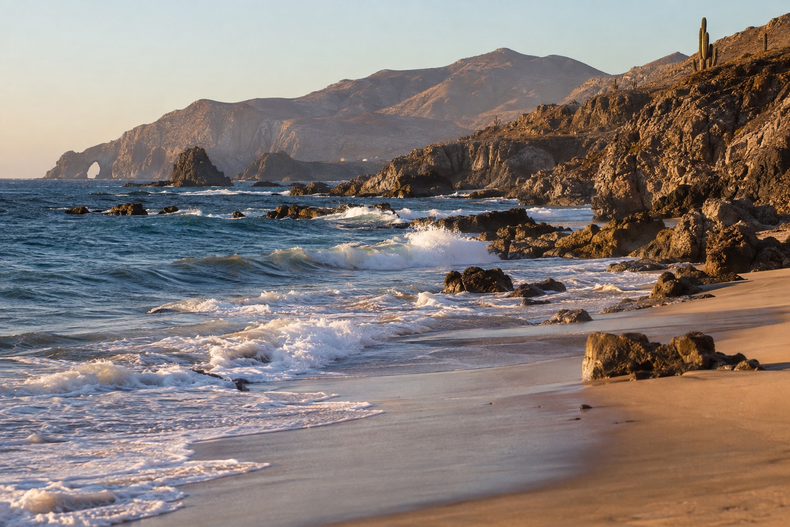 Waves rolling onto a wide sandy beach along the Rosarito oceanfront in warm evening light