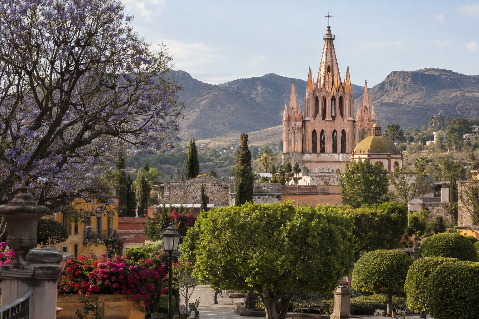 Pink neo-Gothic towers of a parish church rising above a tree-lined plaza in a colonial Mexican town