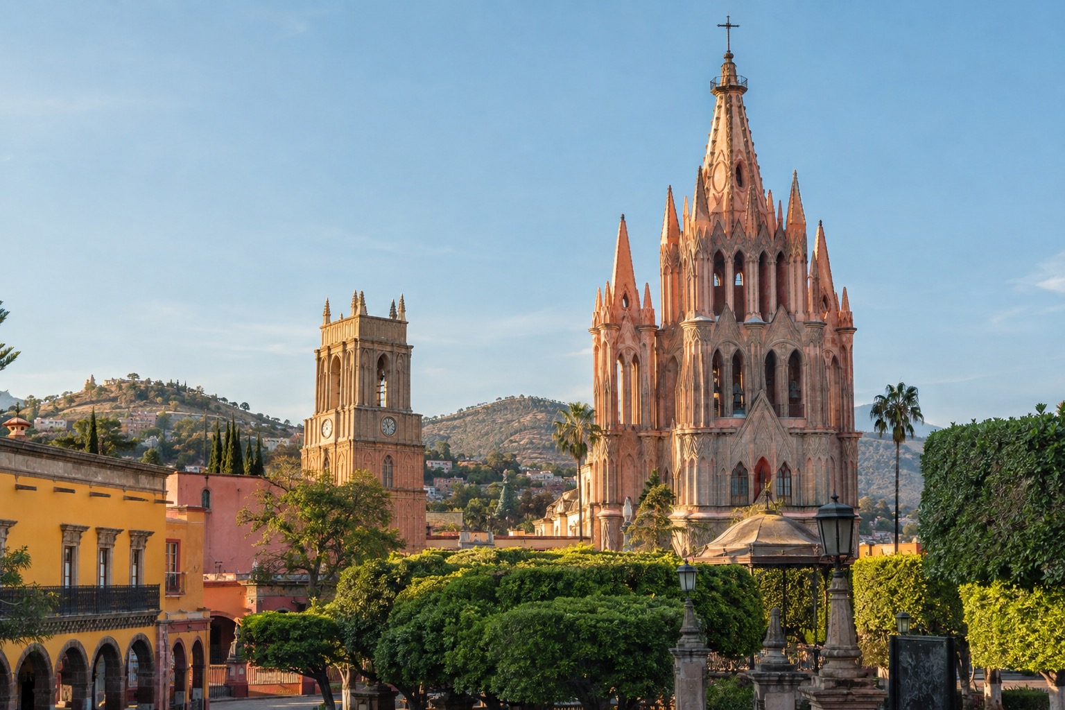 Pink neo-Gothic church towers rising above a tree-lined plaza in San Miguel de Allende