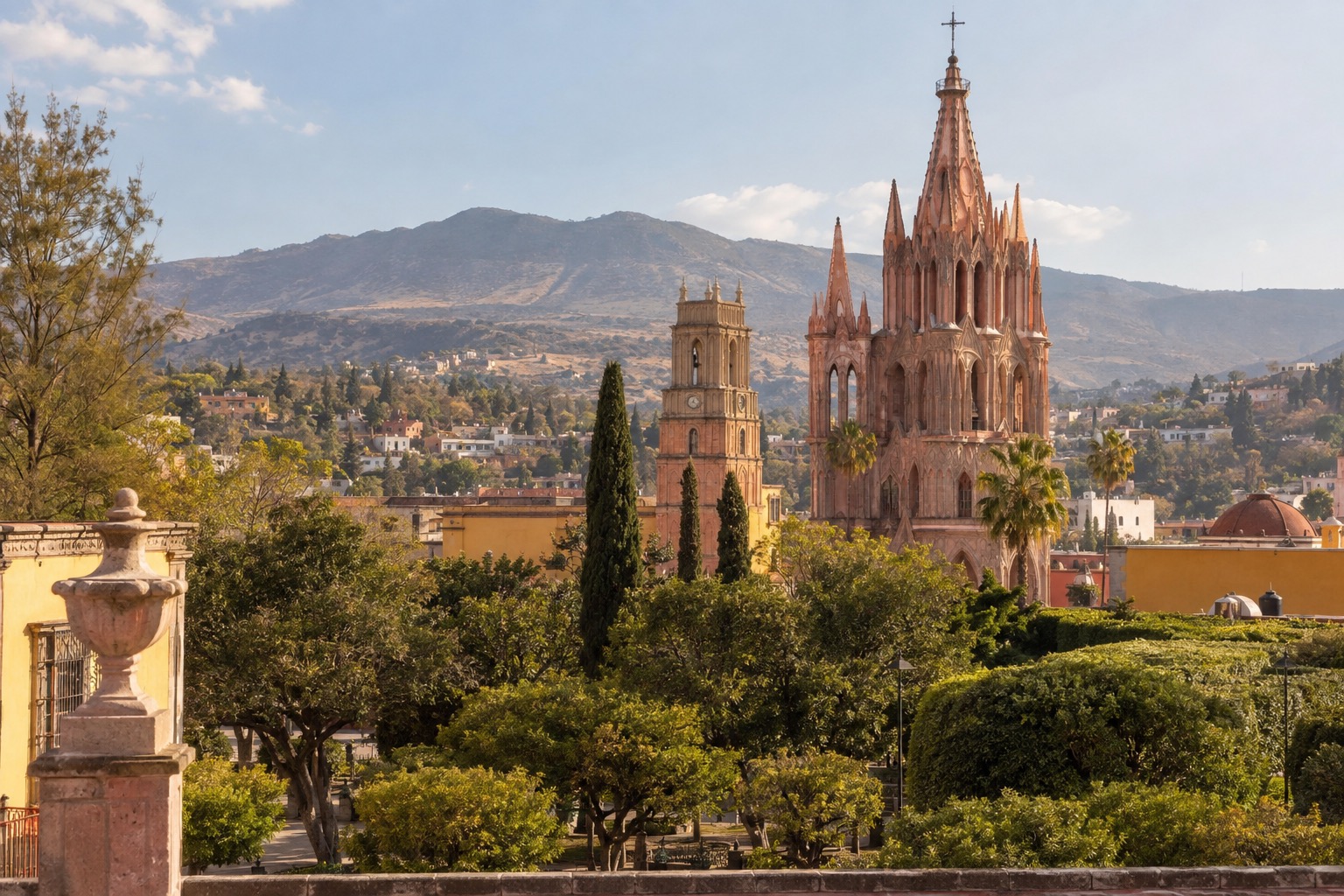 Pink neo-Gothic towers of a parish church rising above a tree-lined plaza in a colonial Mexican town