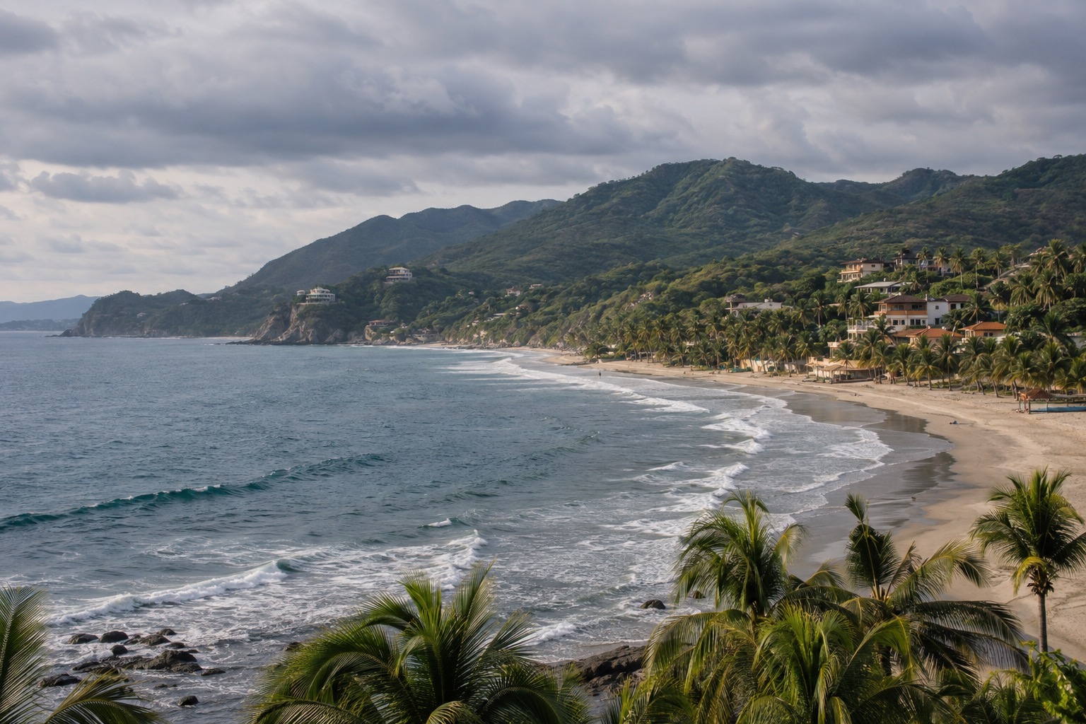 Surf town beach with palm trees and a green hillside under a cloudy sky