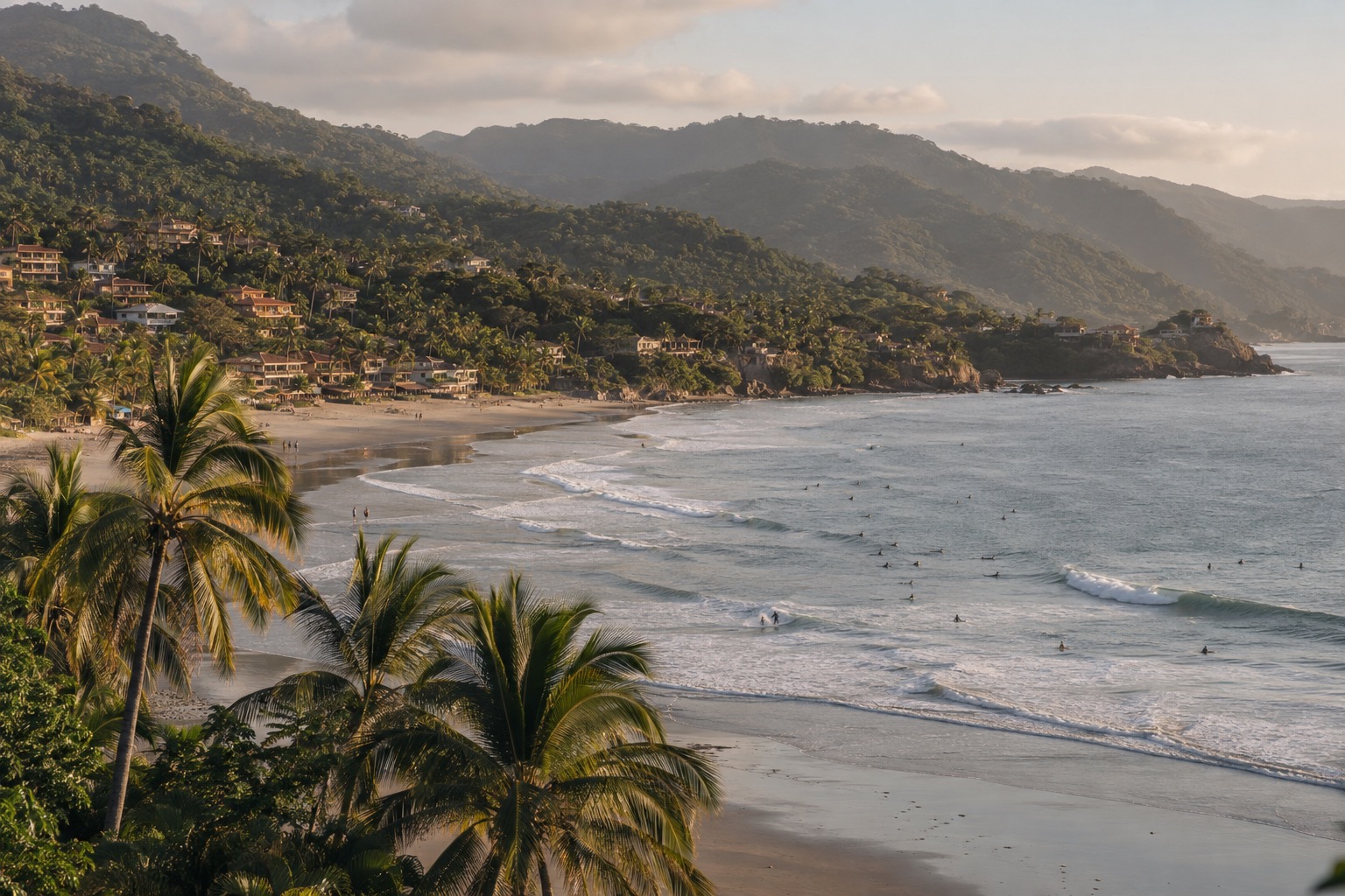 Palm trees behind a wide sandy bay with surfers in the water on the Nayarit coast