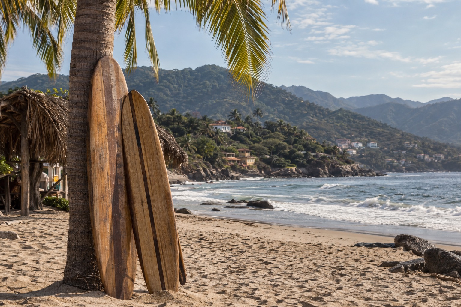 Wooden surfboards leaning against a palm trunk on a sandy beach with low waves behind