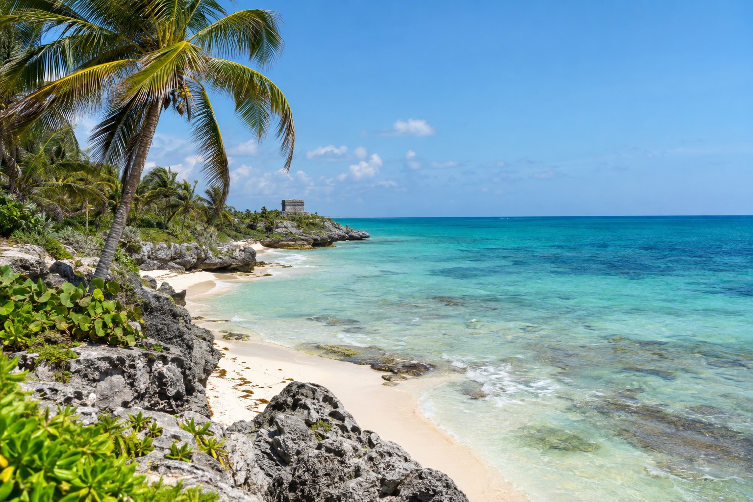 White sand beach and turquoise Caribbean water with palm trees on the coast near Tulum