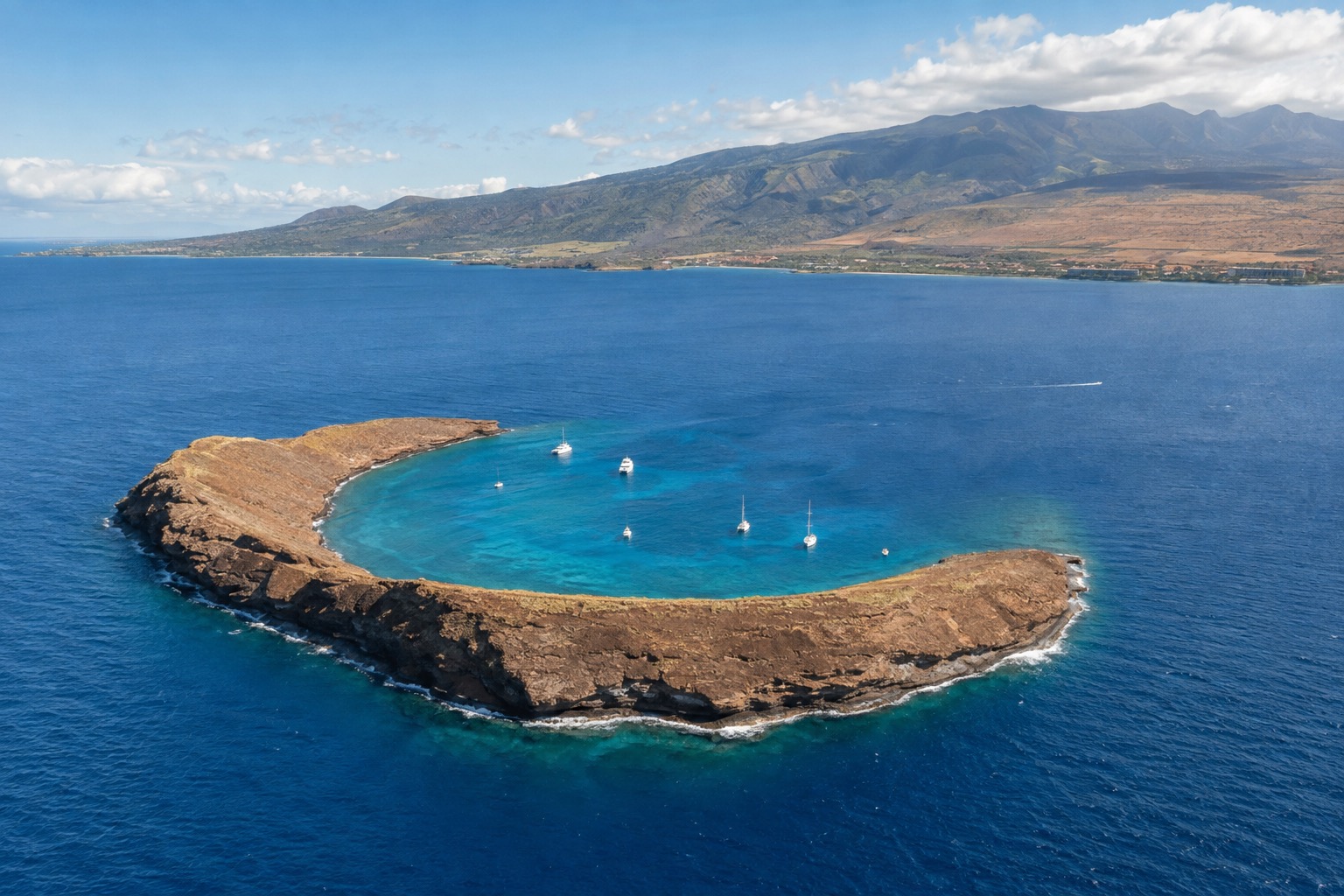 The crescent rim of Molokini crater surrounded by turquoise water off Maui's south coast