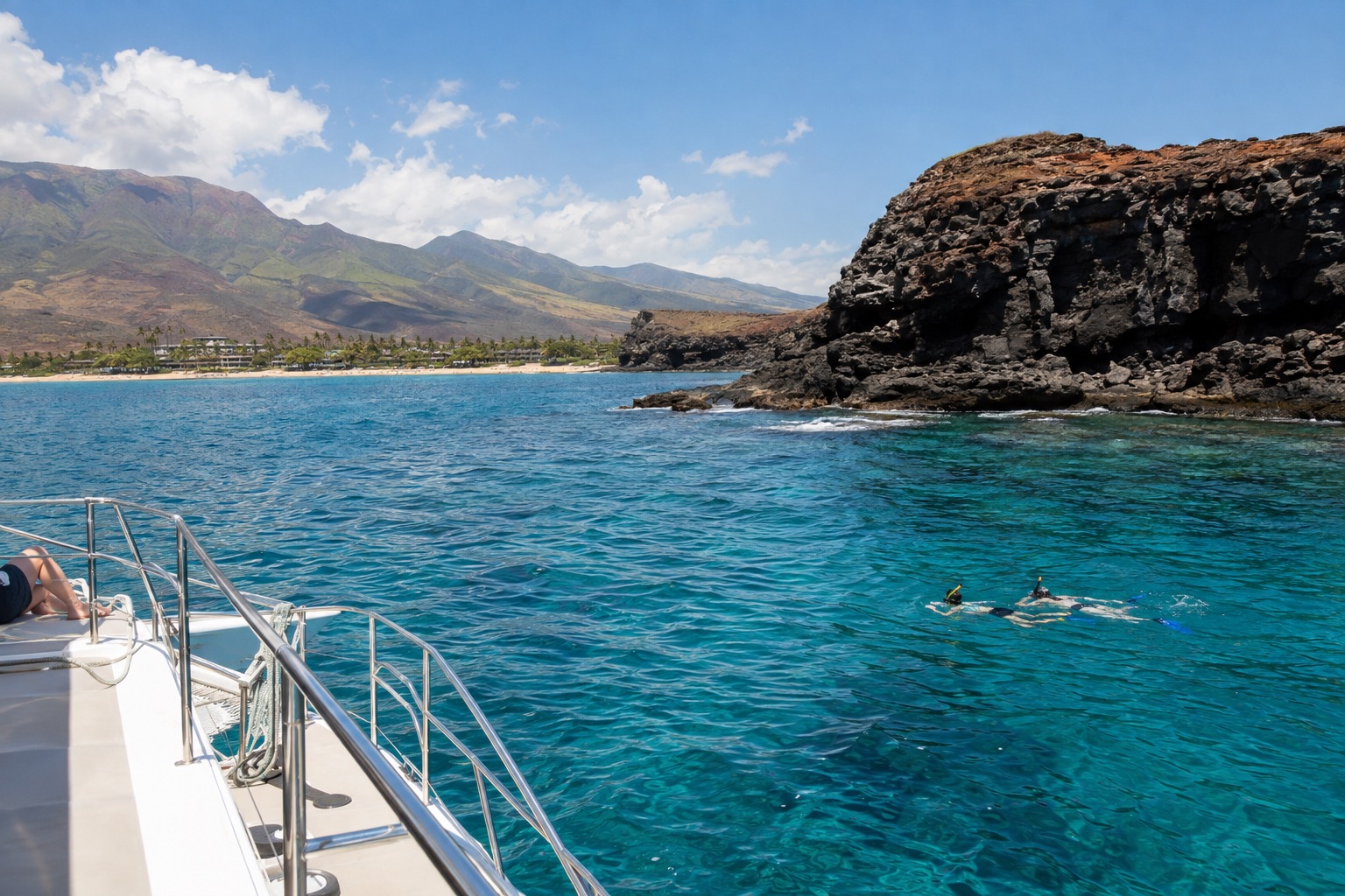 A snorkeling boat anchored beside a crescent-shaped volcanic crater rim rising from turquoise water offshore
