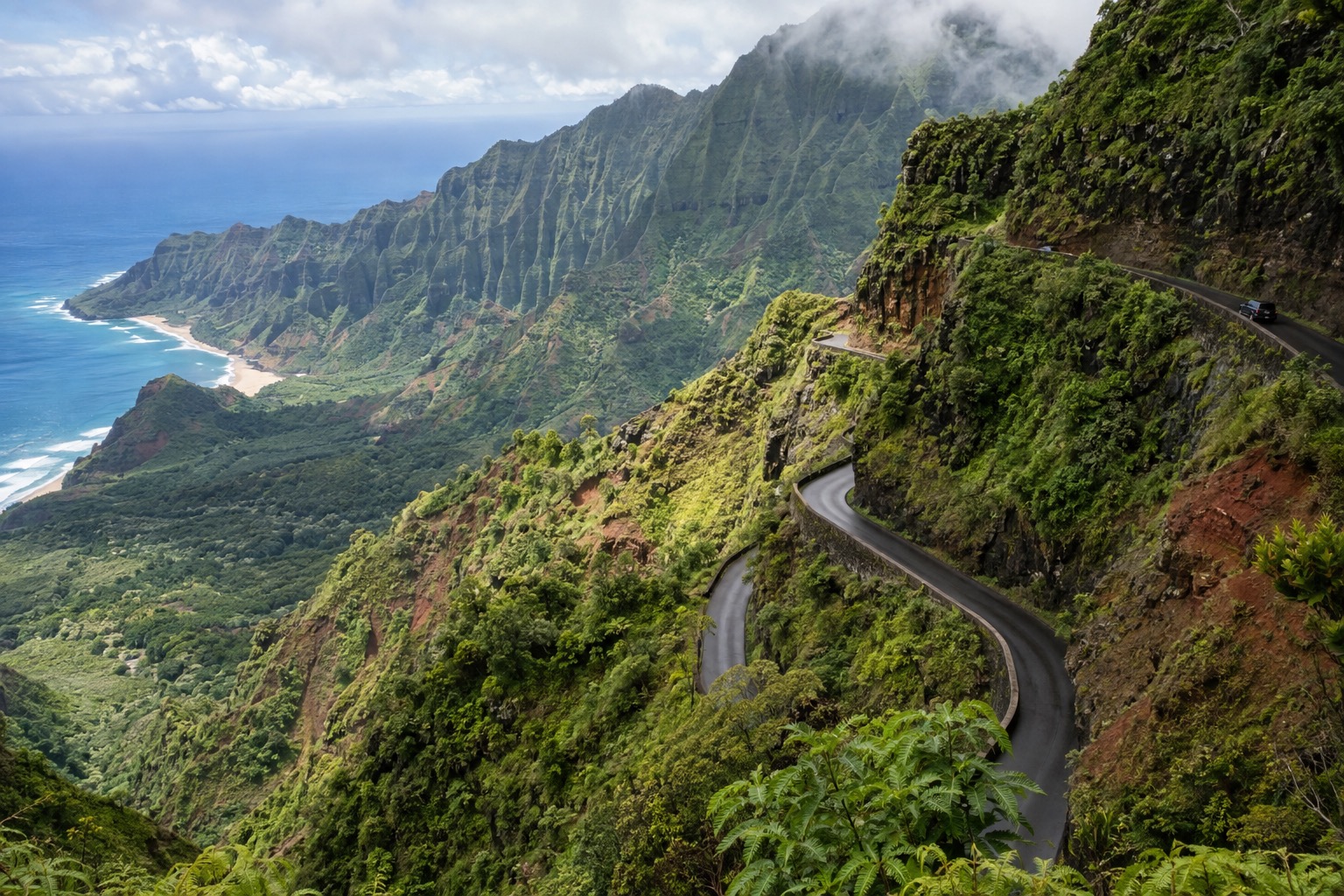 Steep switchback road cut into a green, rain-streaked canyon wall