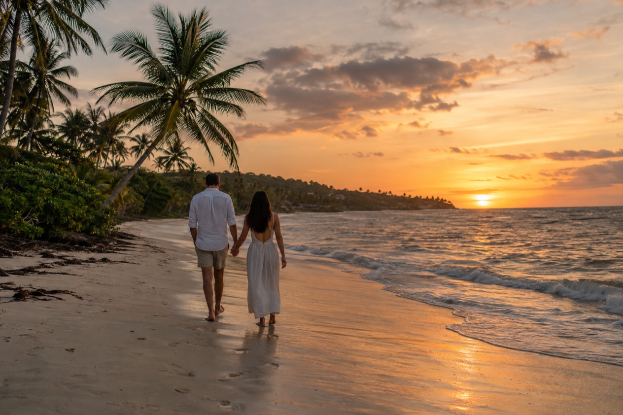 A couple walking on a beach at sunset