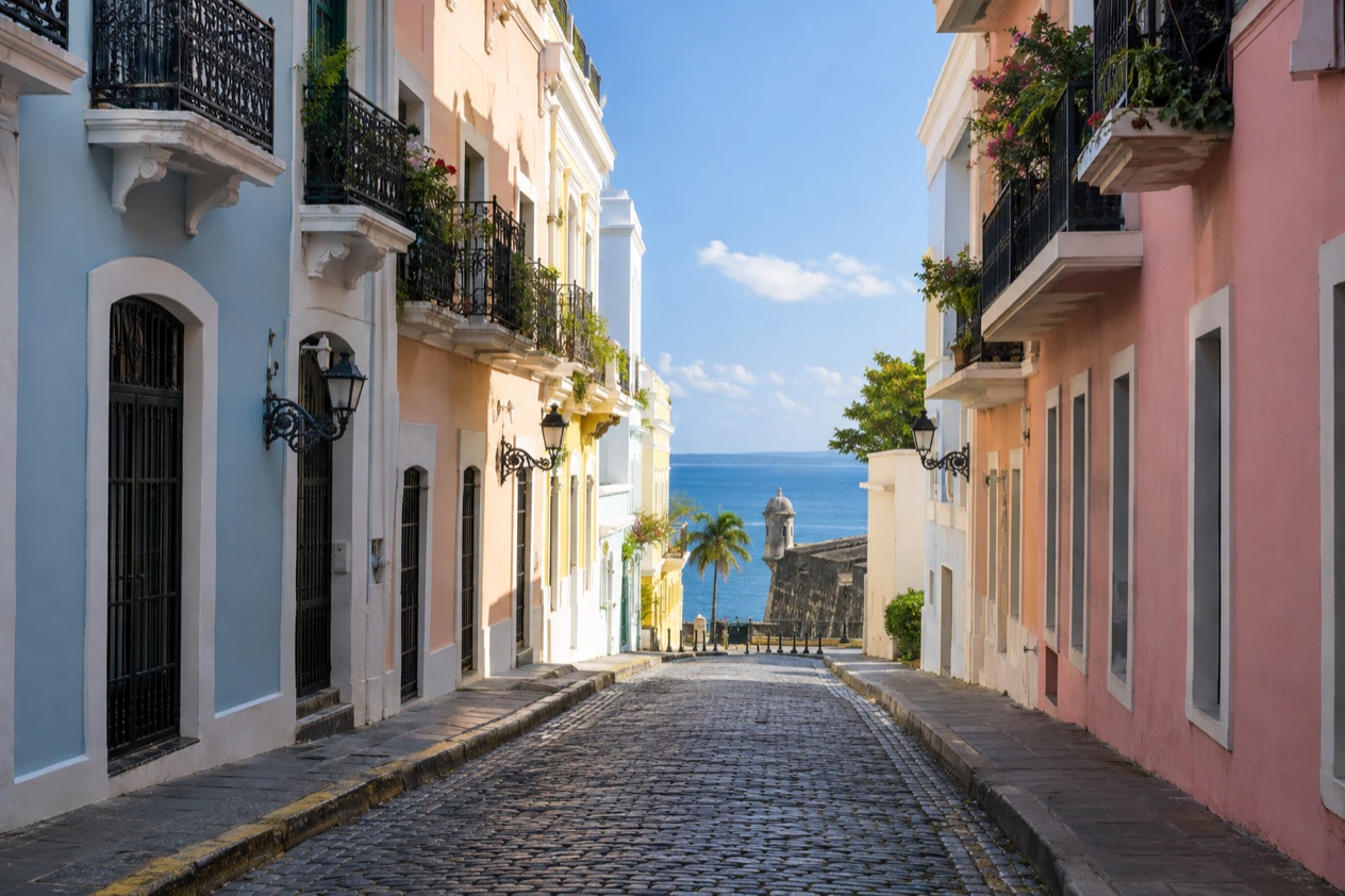 A cobblestone street in Old San Juan between pastel colonial houses in the drier season