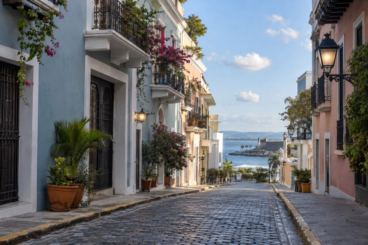 A cobblestone street in Old San Juan between pastel colonial houses in the drier season