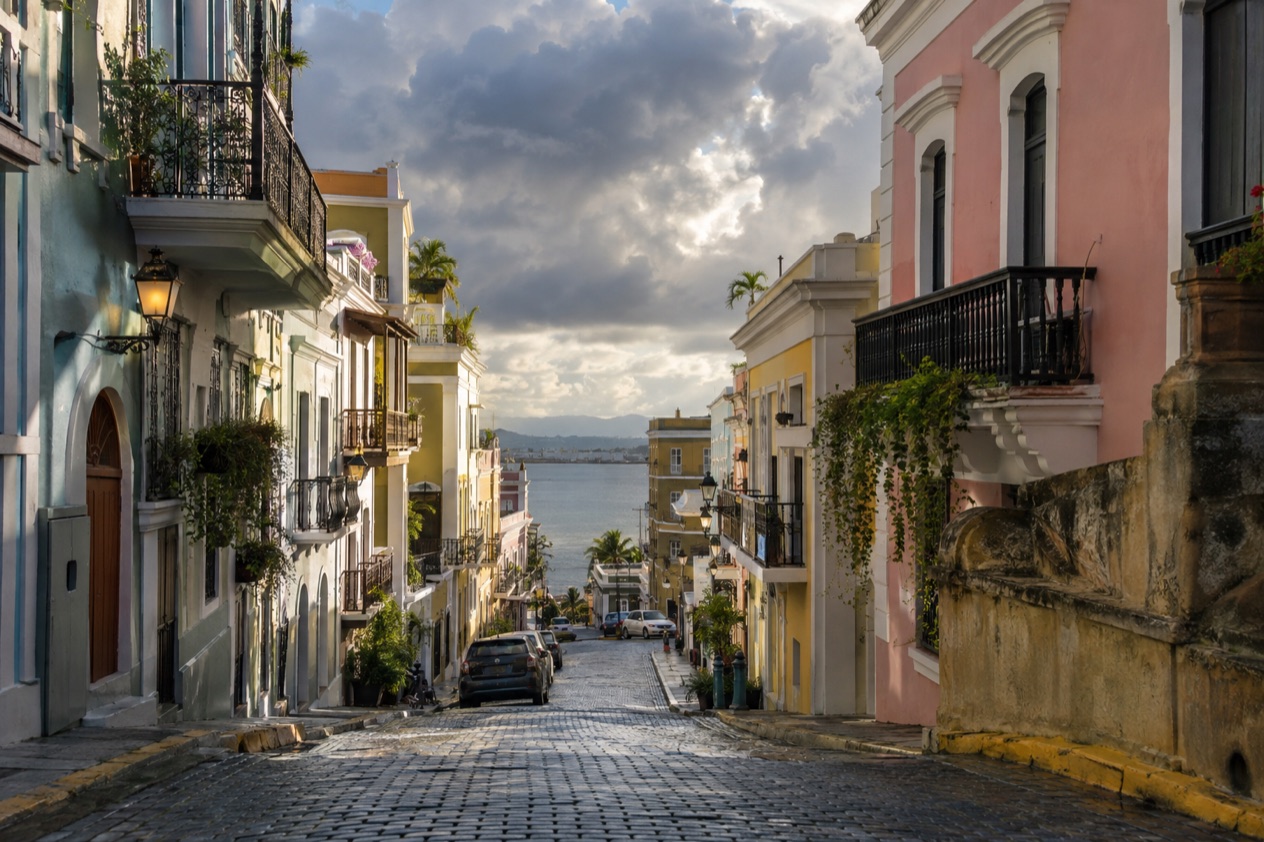 A cobblestone street in Old San Juan between pastel colonial houses in the wetter months